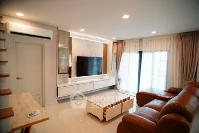 Modern living room with leather sofa, wall-mounted TV, and elegant decor