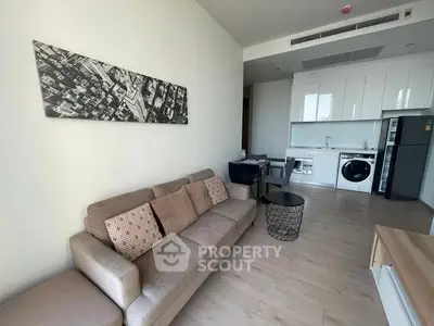 Modern living room with open kitchen, featuring sleek appliances and stylish decor.