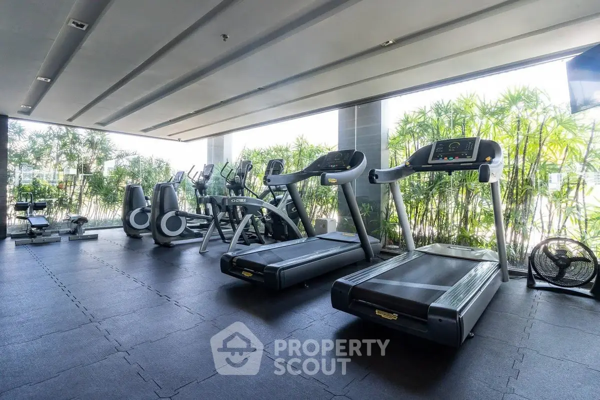 Modern gym with state-of-the-art equipment and lush greenery view, perfect for fitness enthusiasts.