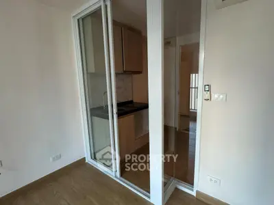 Compact kitchen with sliding glass doors and modern wooden cabinetry.