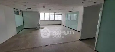 Spacious office space with large windows and modern flooring in a high-rise building.