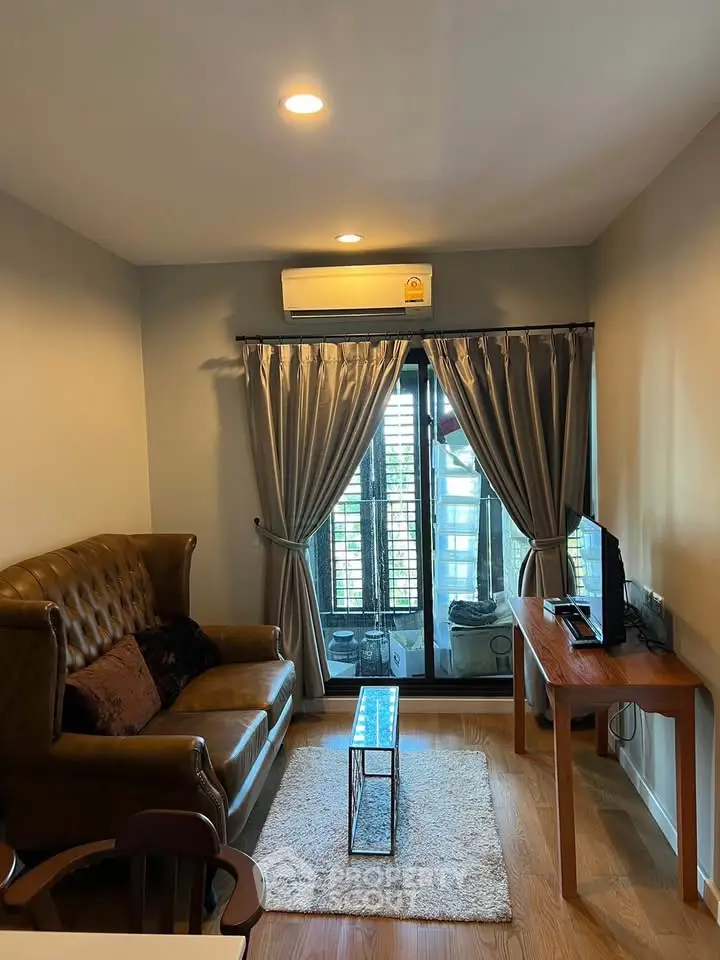 Cozy living room with leather sofa, TV, and balcony access in modern apartment.