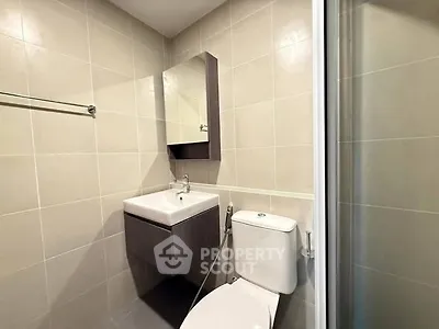 Modern bathroom with sleek fixtures and neutral tiles, featuring a compact design for efficient space use.