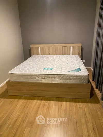 Modern bedroom with wooden flooring and stylish bed frame, perfect for cozy living.