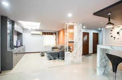 Spacious modern living room with elegant marble accents and cozy seating area.