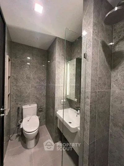 Modern bathroom with sleek gray tiles and glass shower enclosure