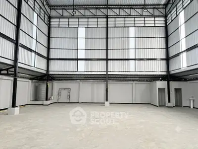 Spacious industrial warehouse with high ceilings and ample natural light, perfect for storage or manufacturing.