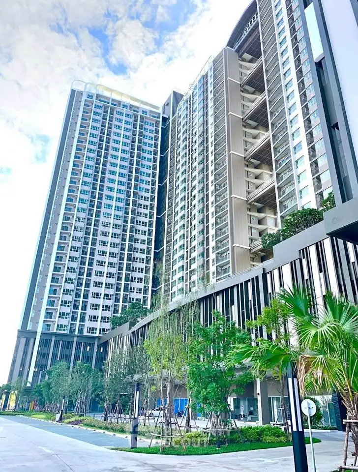 Modern high-rise residential building with lush landscaping and clear blue sky.