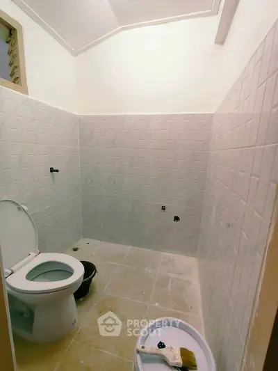 Spacious bathroom with modern tiling and toilet, ideal for renovation projects.