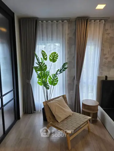 Stylish living room with modern chair, lush plant, and elegant curtains.