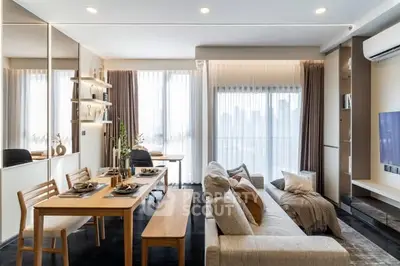 Modern living room with dining area, stylish decor, and large windows offering city views.