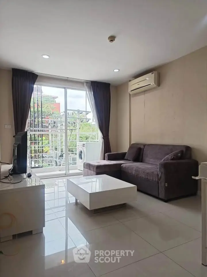 Modern living room with balcony view, featuring sleek furniture and air conditioning.