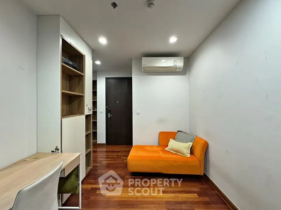 Modern living room with orange sofa and wooden flooring, featuring a sleek air conditioning unit.