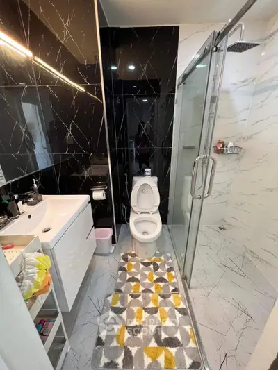 Modern bathroom with sleek black and white marble tiles and glass shower enclosure.