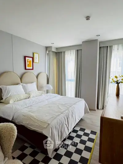 Modern bedroom with stylish decor and natural light, featuring a cozy bed and elegant furnishings.