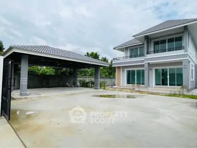 Spacious modern two-story house with large driveway and covered parking area, surrounded by lush greenery.
