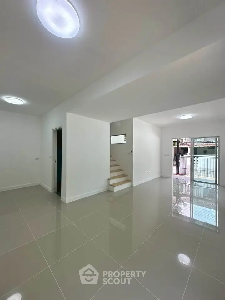 Spacious modern living room with glossy tiled floors and staircase, perfect for contemporary living.
