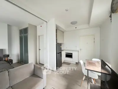 Modern open-plan living room with kitchen and dining area, featuring sleek furniture and neutral tones.