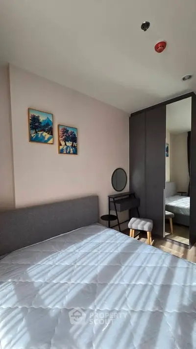 Cozy bedroom with modern decor and ample natural light, featuring a stylish wardrobe and vanity area.