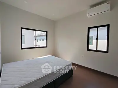 Spacious bedroom with natural light and modern air conditioning unit.
