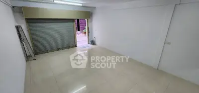 Spacious empty room with tiled floor and open garage door, ideal for commercial use.