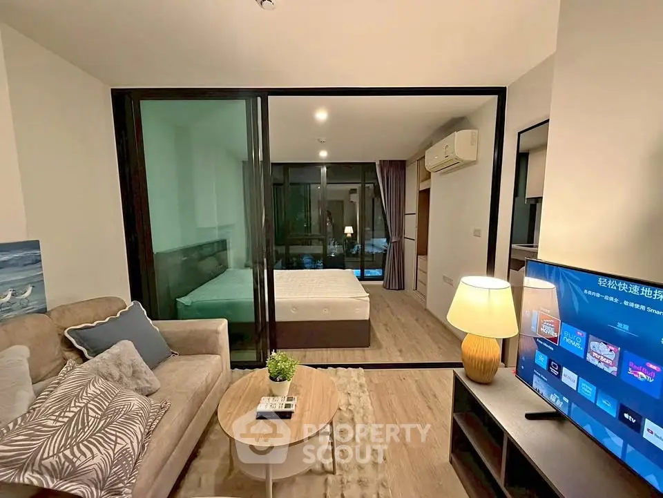 Modern living room with cozy seating and view into stylish bedroom