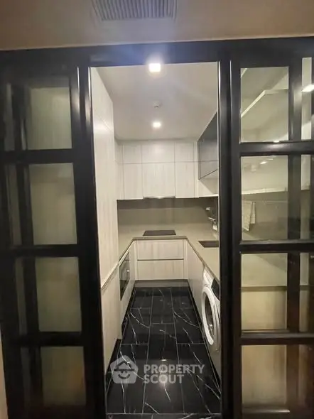 Modern compact kitchen with sleek black flooring and built-in appliances.