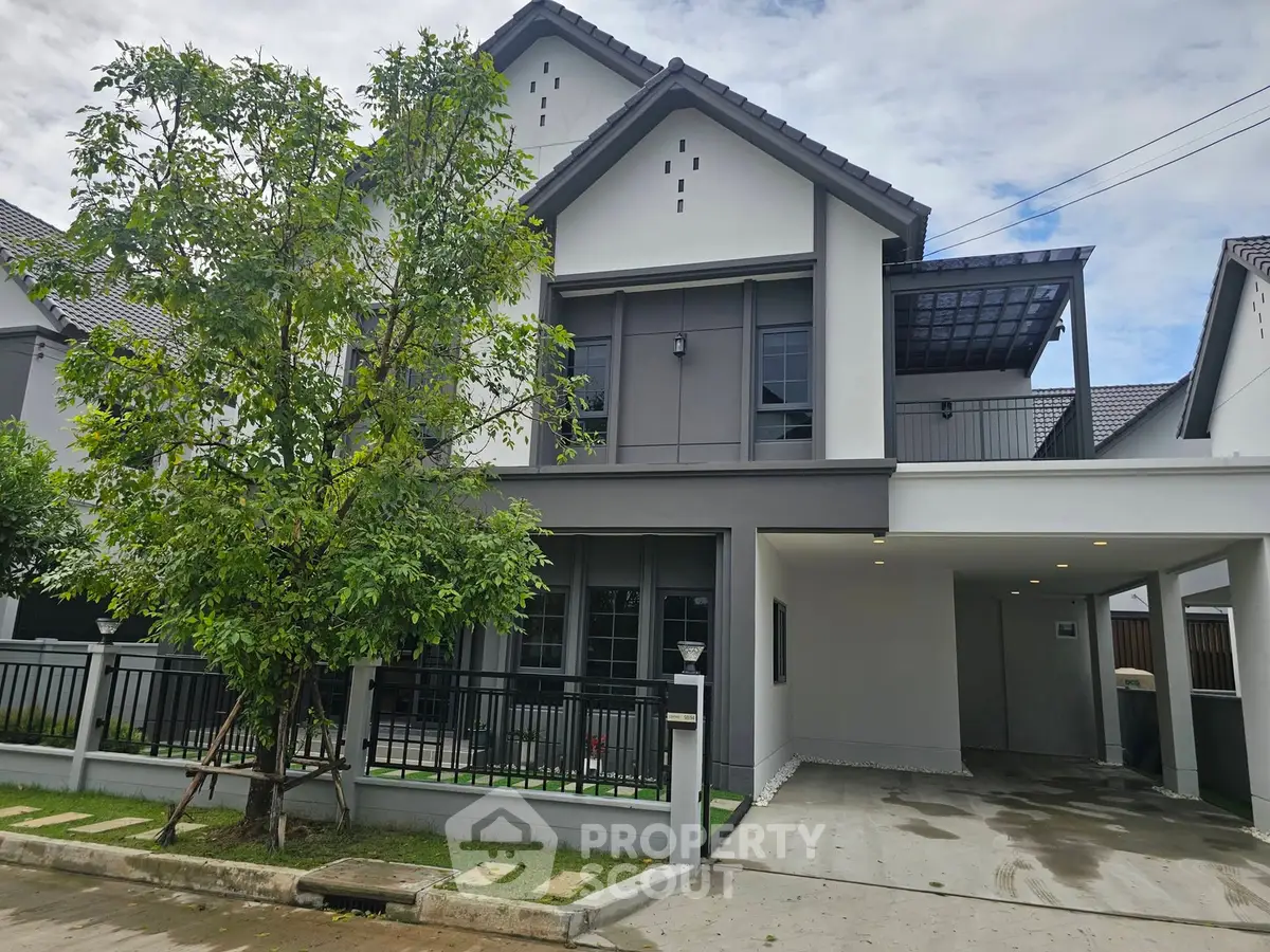 Modern two-story house with spacious driveway and lush greenery in a serene neighborhood.