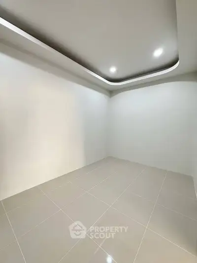 Minimalist empty room with modern recessed lighting and sleek tiled flooring.