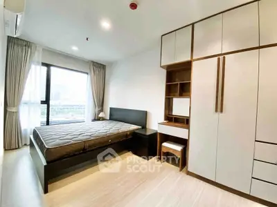 Modern bedroom with large window and built-in wardrobe in a stylish apartment.