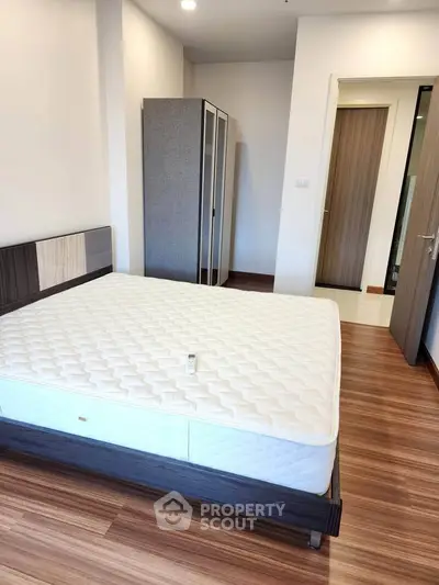Spacious bedroom with modern design and wooden flooring, featuring a comfortable bed and ample storage space.