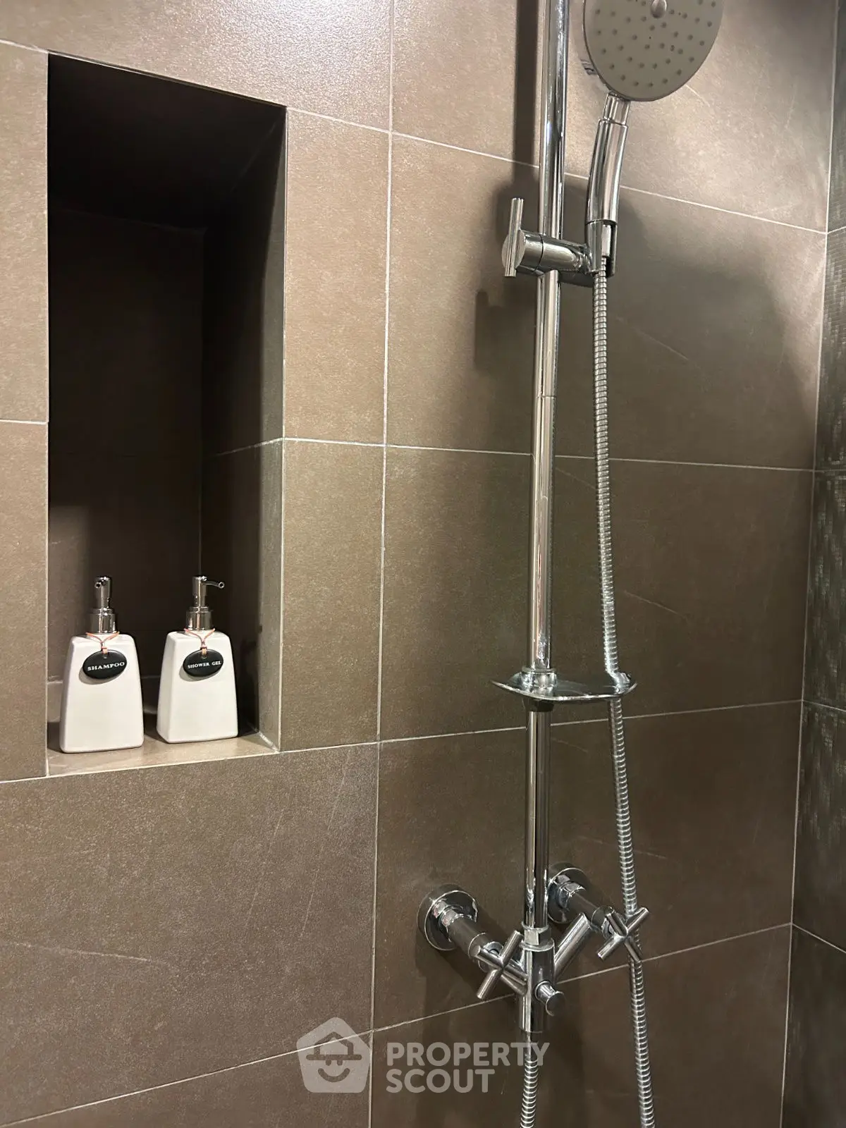 Modern bathroom shower with sleek chrome fixtures and built-in shelf.