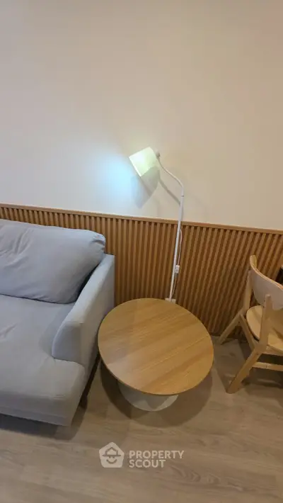 Modern living room with stylish sofa, wooden side table, and sleek floor lamp.