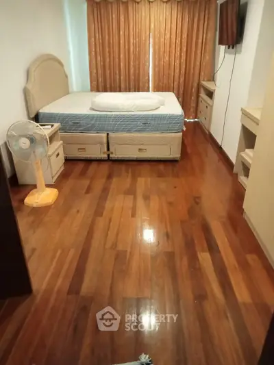 Spacious bedroom with wooden flooring and modern furnishings