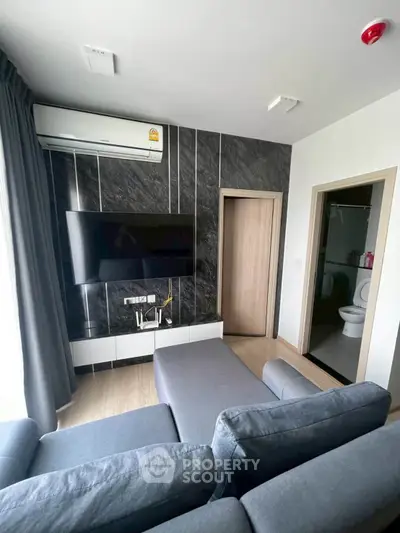Modern living room with sleek design, featuring a wall-mounted TV and stylish gray sofa.