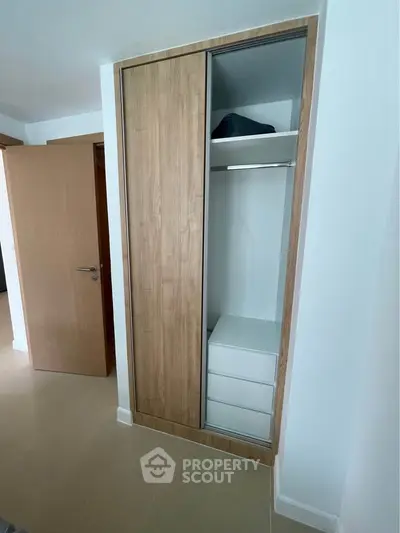 Modern wooden wardrobe with sliding doors in a minimalist bedroom setting.