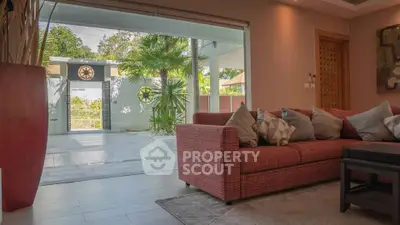 Spacious living room with modern sofa and large glass doors opening to a lush garden view.