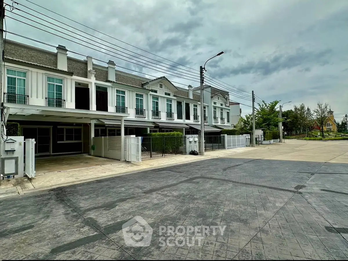 Modern townhouse complex with spacious driveways and lush greenery.