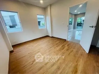 Spacious empty room with wooden flooring and large windows