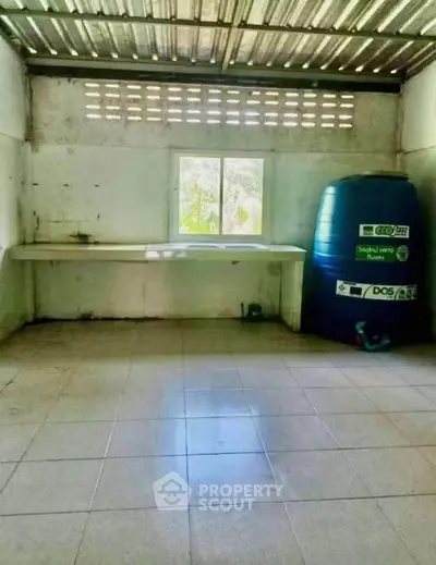 Spacious utility room with large water tank and window view.
