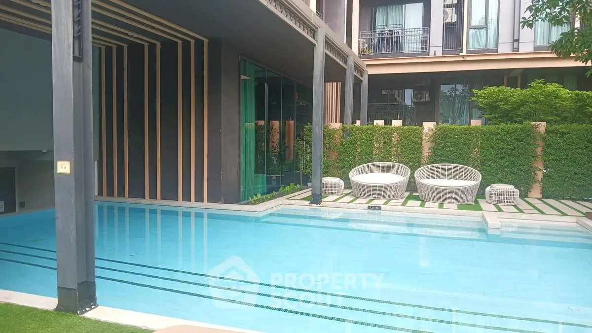 Luxurious modern poolside area with stylish seating and lush greenery in a contemporary building.
