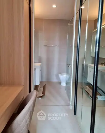 Modern bathroom with glass shower and sleek fixtures in contemporary apartment.