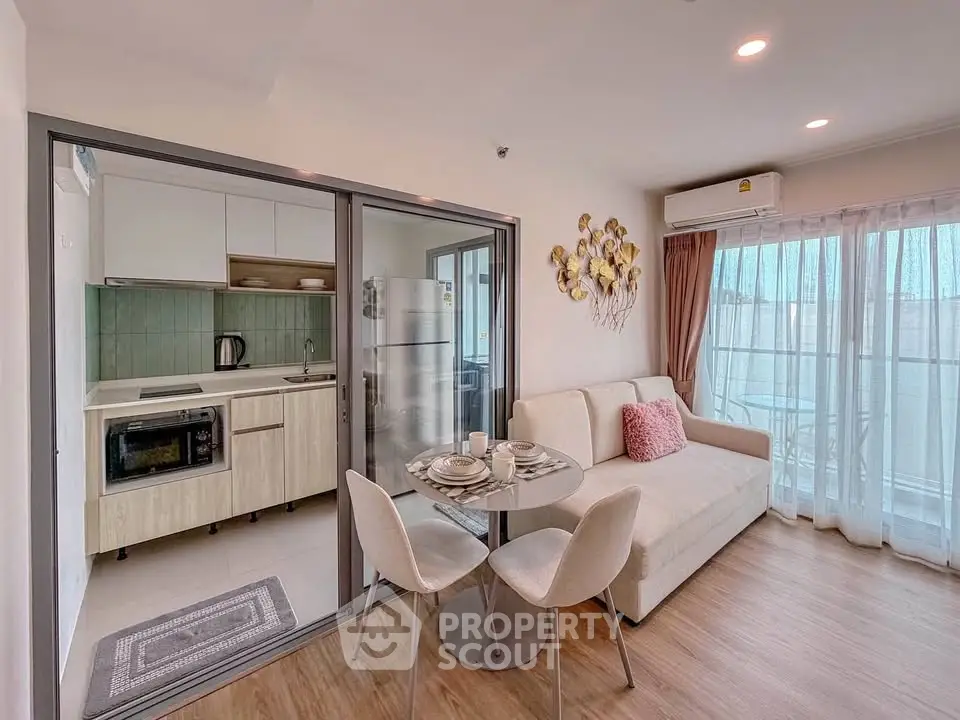 Modern living room with open kitchen and balcony access, featuring stylish decor and natural light.