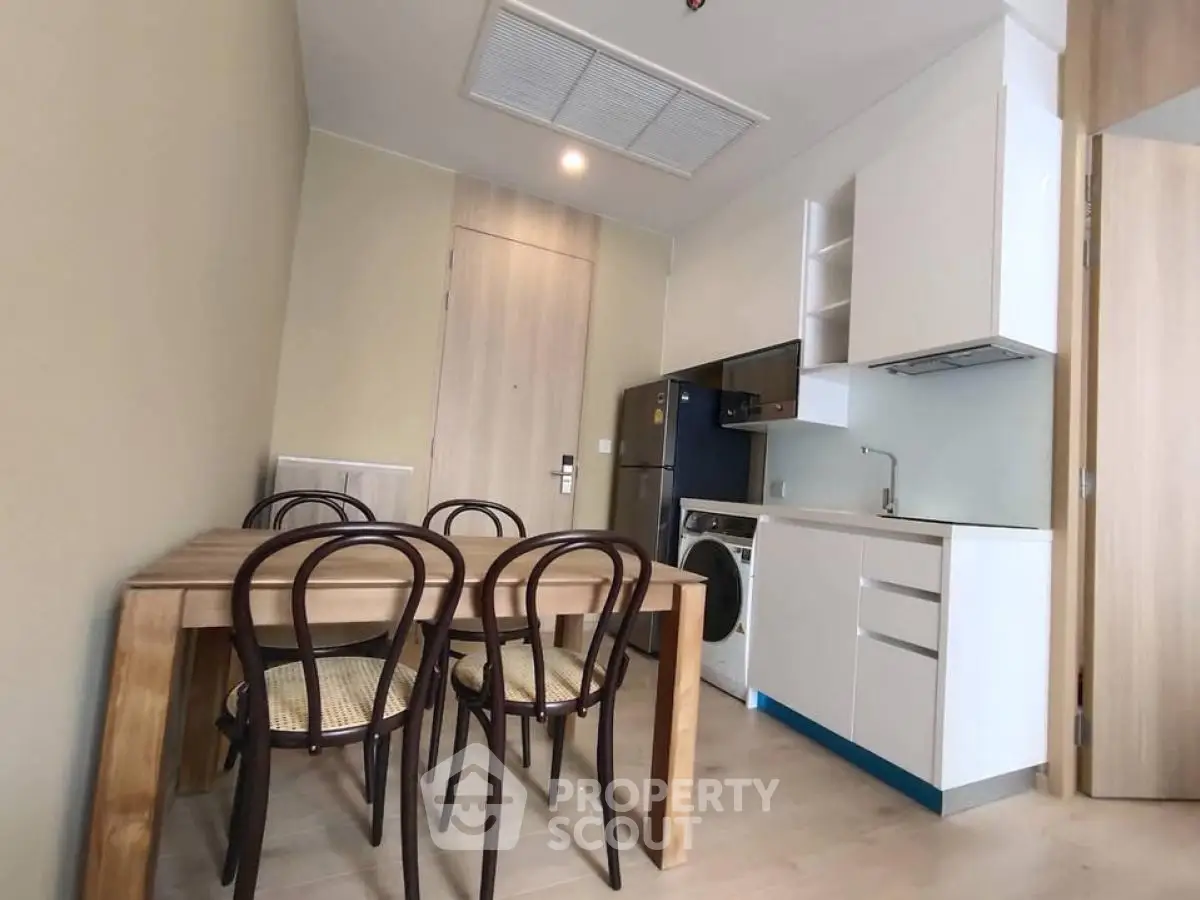 Modern compact kitchen with dining area and washing machine in cozy apartment.