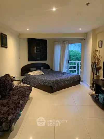 Spacious bedroom with modern decor and balcony view in urban apartment