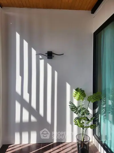 Charming balcony with modern wall light and potted plant, perfect for relaxation.