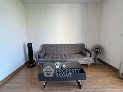 Modern living room with sleek gray sofa and stylish coffee table on wooden flooring.