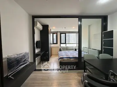 Modern studio apartment with glass partition, featuring a cozy bedroom and sleek living area.