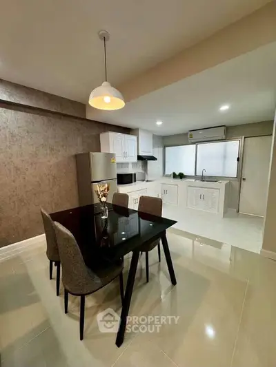 Modern kitchen with dining area featuring sleek black table and stylish chairs, perfect for contemporary living.