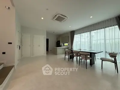 Spacious modern living room with dining area and large windows in a stylish home.